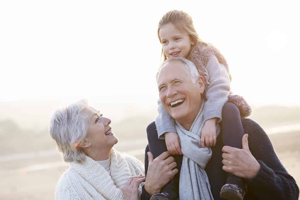 Grandparents And Granddaughter Walking On Winter Beach