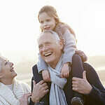 Grandparents And Granddaughter Walking On Winter Beach